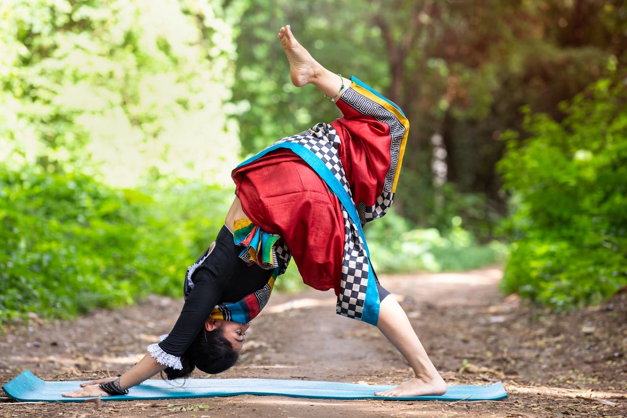 services-01 Woman practicing yoga outdoors in vibrant traditional clothing, showcasing flexibility and harmony with nature.